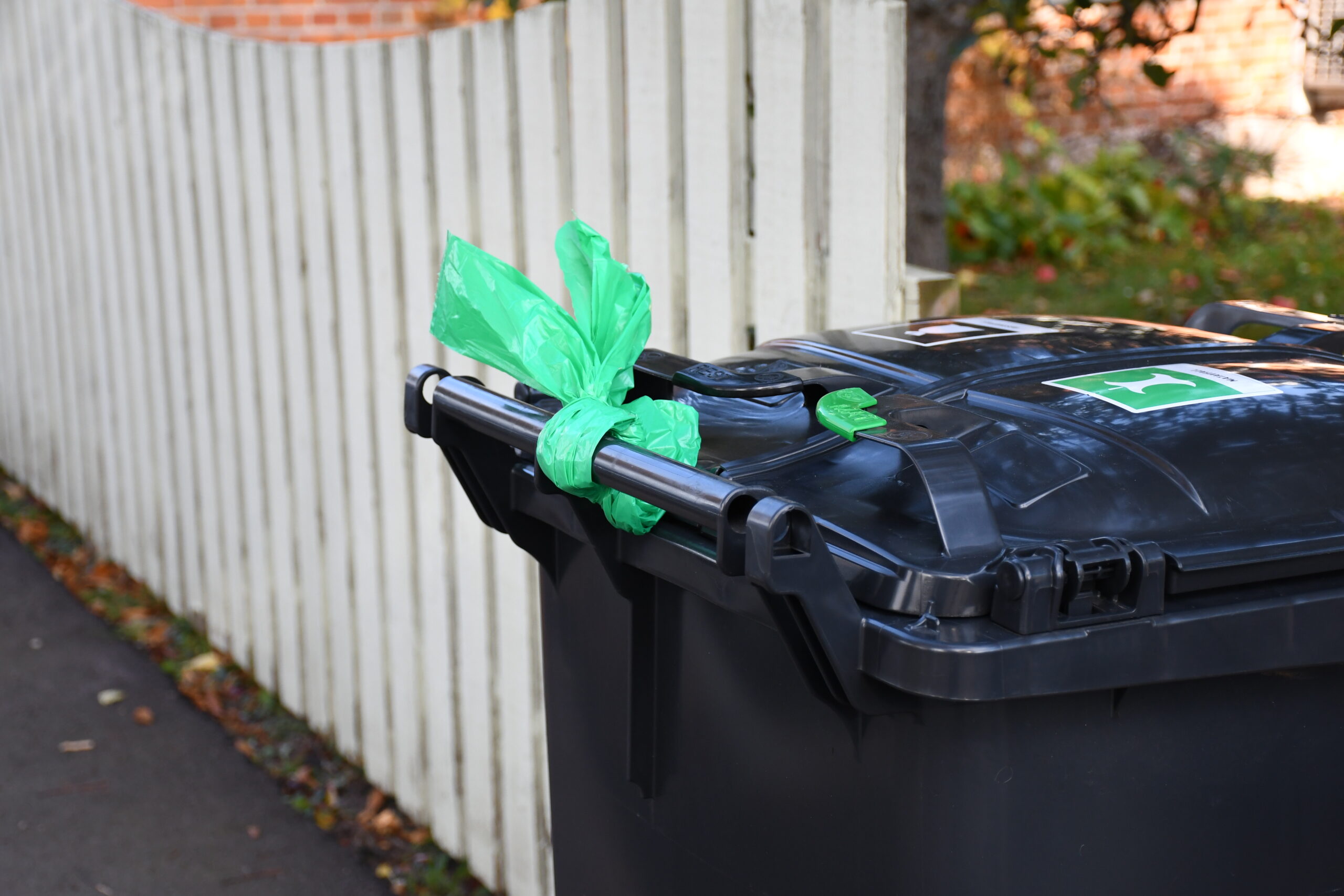 Svart sopkärl med en plastpåse knuten runt handtaget